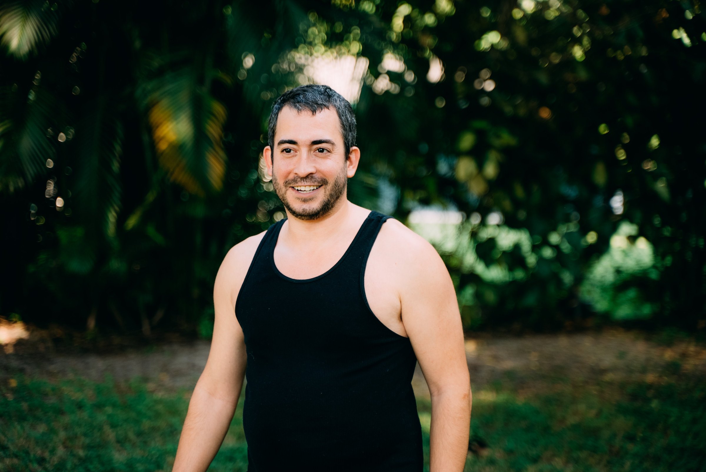 A man in a black tank top standing outdoors