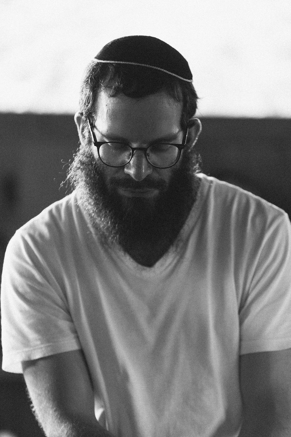 A bearded man in a white shirt and kippah in a quiet moment
