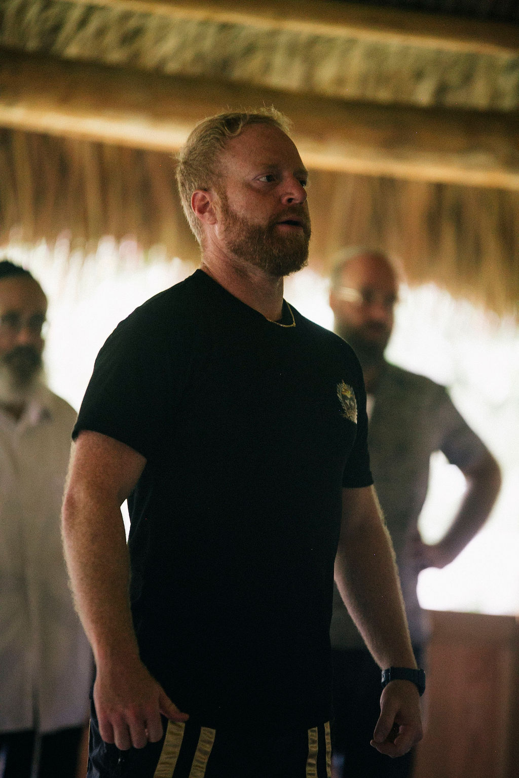 A red haired man standing with other men nearby